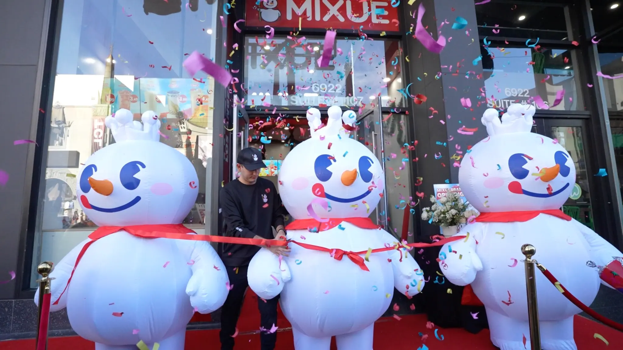 MIXUE grand opening ceremony with ribbon cutting and giant snowman mascots